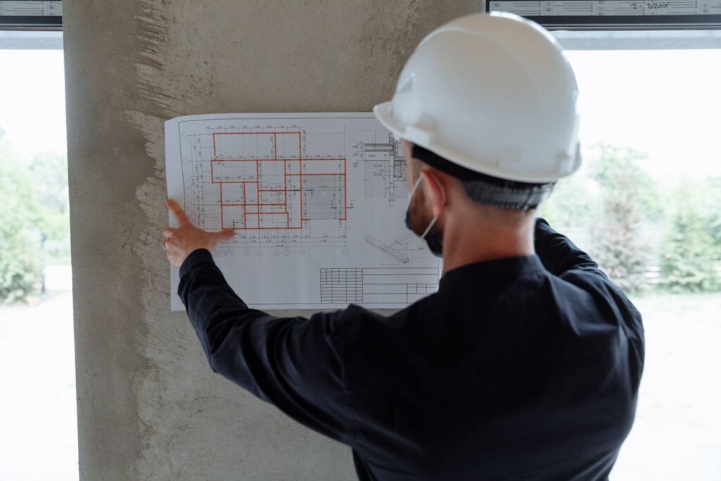 Engineer in a hard hat reviewing a floor plan on site