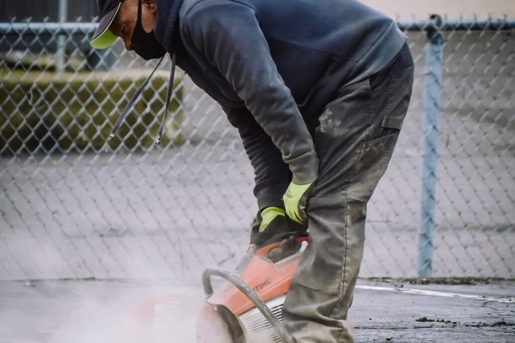 Worker in safety gear cutting out damaged concrete