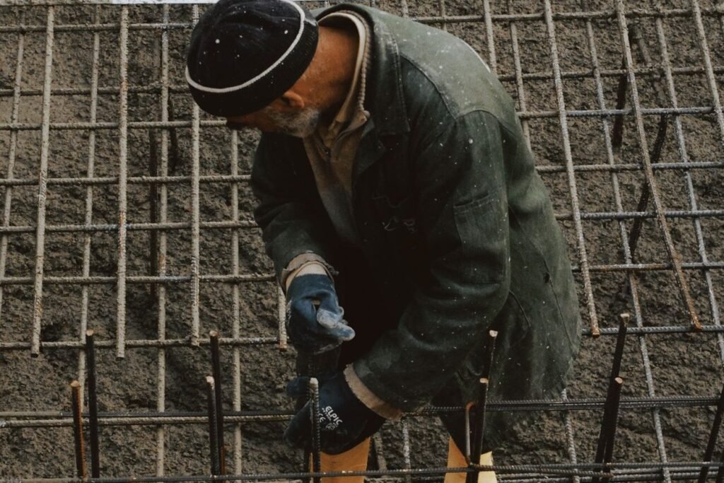 Worker in protective gear securing reinforcement steel before concrete is placed